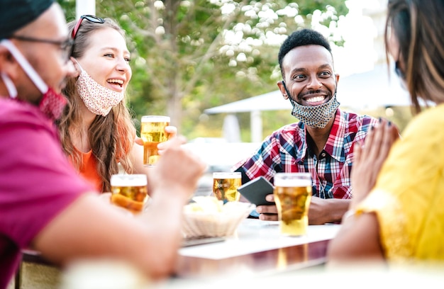 Gente multicultural bebiendo cerveza con mascarillas abiertas