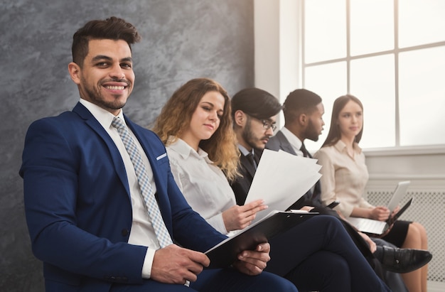 Gente multiétnica esperando en cola. preparándose para la entrevista de trabajo, solicitantes de vacantes desempleados leyendo cv, espacio de copia