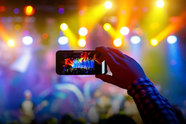 La gente en la multitud en un concierto hace grabaciones de video y fotos en un teléfono inteligente