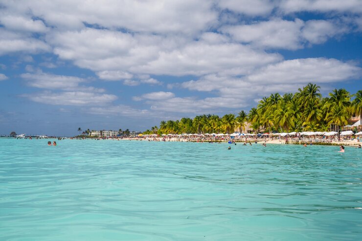 Foto gente nadando cerca de la playa de arena blanca con sombrillas bungalow bar y palmeras cocos mar caribe turquesa isla mujeres isla mar caribe cancún yucatán méxico