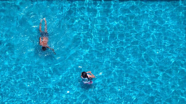 Gente nadando en la piscina del hotel el día de vacaciones de verano y jugando juntos en familia y en el ángulo de visión superior.