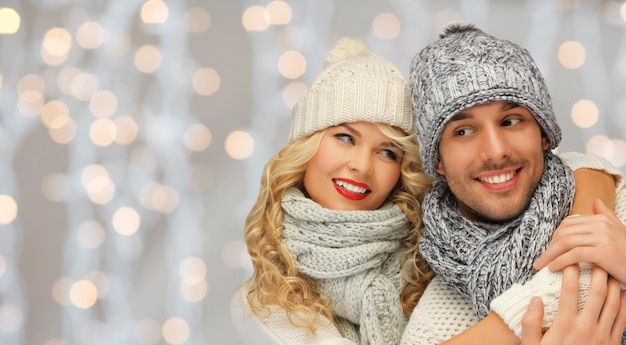 gente, navidad, vacaciones y concepto de año nuevo - pareja familiar feliz con ropa de invierno abrazándose sobre el fondo de las luces