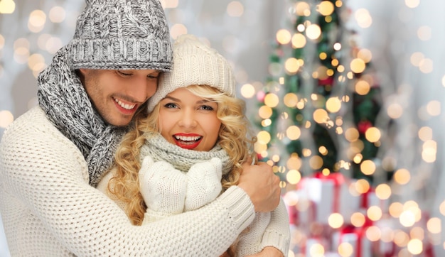 gente, navidad, vacaciones y concepto de año nuevo - pareja familiar feliz con ropa de invierno abrazándose sobre el fondo de las luces