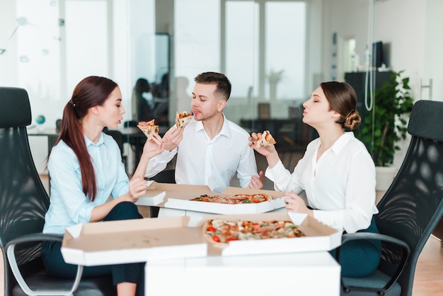 Gente de negocios almorzando pizza en la oficina