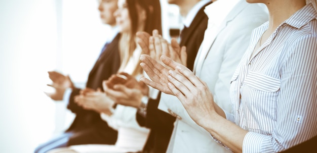 Foto gente de negocios aplaudiendo y aplausos en reuniones o conferencias, primer plano de manos. grupo de hombres y mujeres de negocios desconocidos en la oficina blanca moderna. trabajo en equipo de éxito o concepto de coaching corporativo.