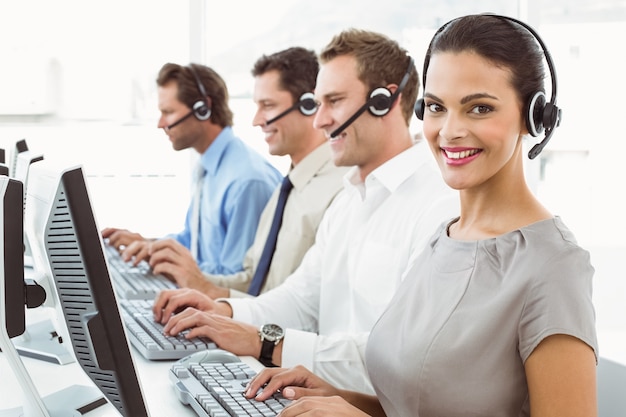 Gente de negocios con auriculares usando computadoras en la oficina