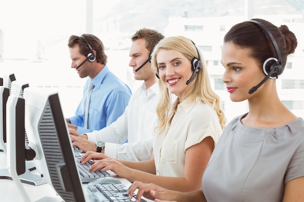 Gente de negocios con auriculares utilizando computadoras en la oficina