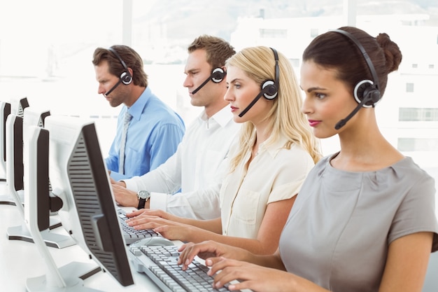 Gente de negocios con auriculares utilizando computadoras en la oficina