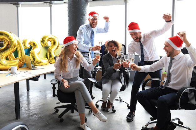Foto la gente de negocios está celebrando las vacaciones en la oficina moderna bebiendo champán y divirtiéndose en el coworking. feliz navidad y próspero año nuevo 2022.