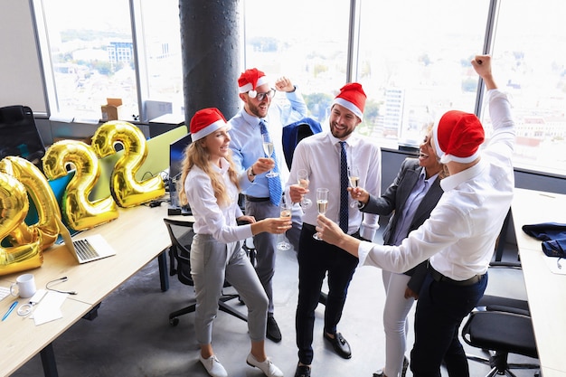 Foto la gente de negocios está celebrando las vacaciones en la oficina moderna bebiendo champán y divirtiéndose en el coworking. feliz navidad y próspero año nuevo 2022.