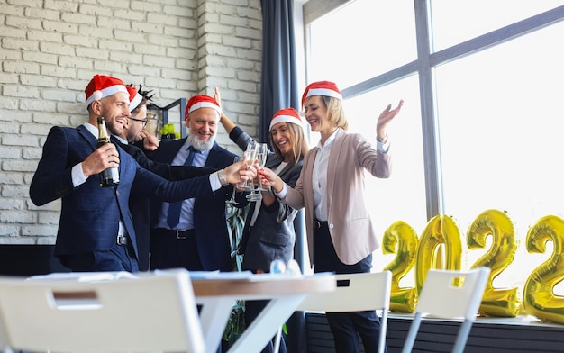 Foto la gente de negocios está celebrando las vacaciones en la oficina moderna bebiendo champán y divirtiéndose en el coworking. feliz navidad y próspero año nuevo 2022.