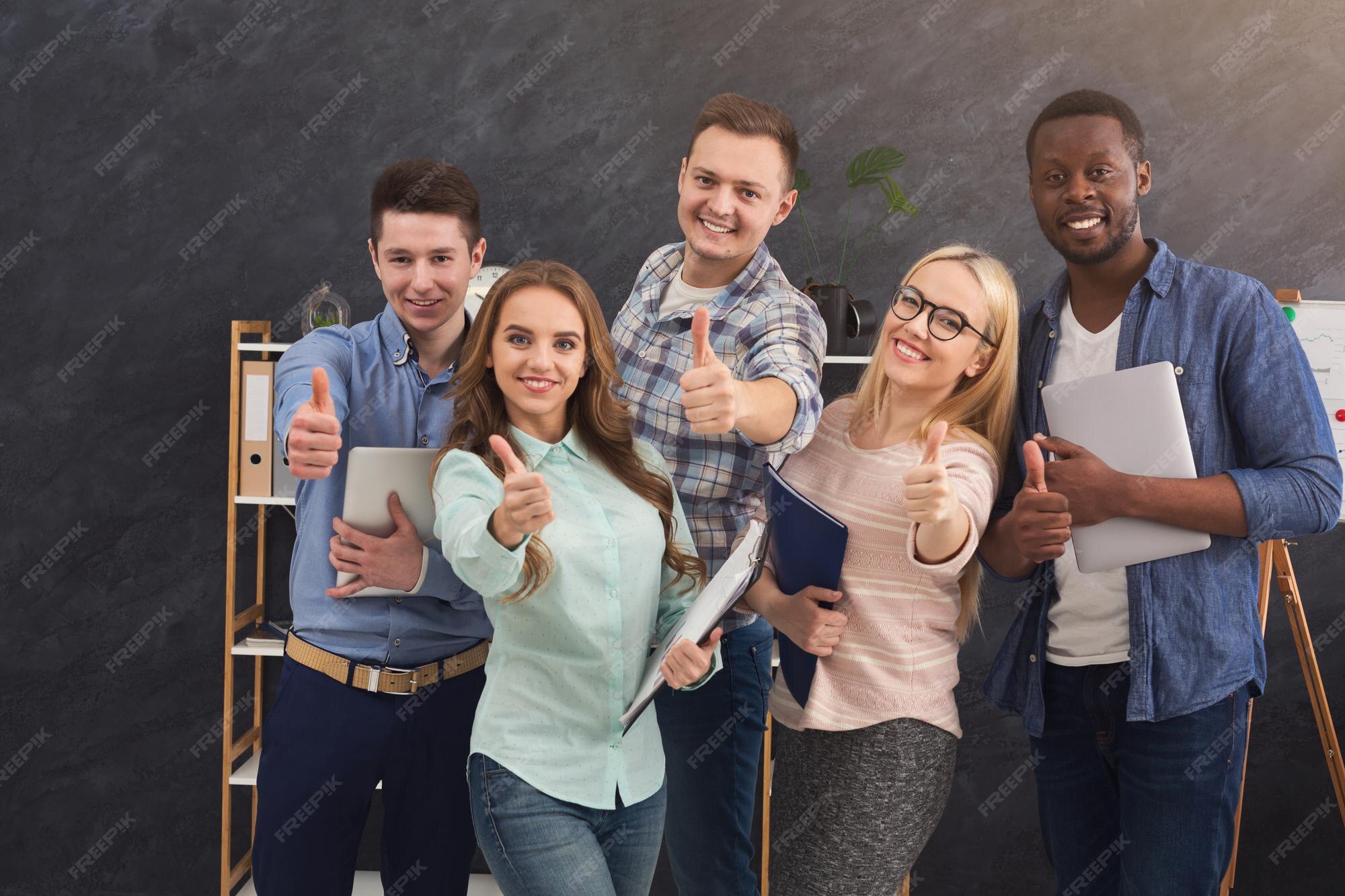 Gente de negocios confiada que muestra los pulgares para arriba gesto en la  oficina. equipo joven exitoso posando para la foto, sonriendo a la cámara,  concepto de motivación y éxito, espacio de