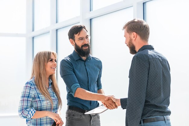 Foto la gente de negocios se dan la mano de pie en la oficina. concepto de cooperación