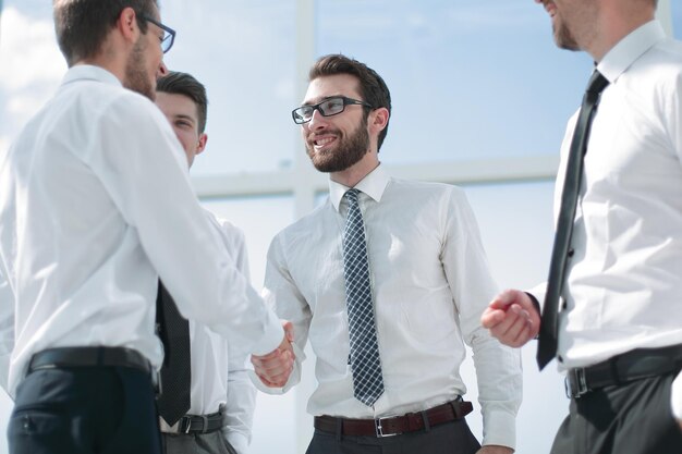 Gente de negocios dándose la mano mientras está de pie en la oficina