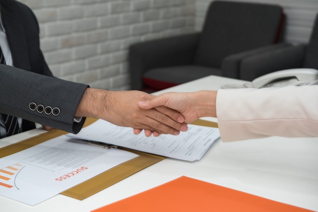 Gente de negocios dándose la mano sobre el escritorio.