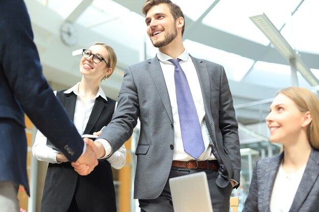 Gente de negocios dándose la mano, terminando una reunión.