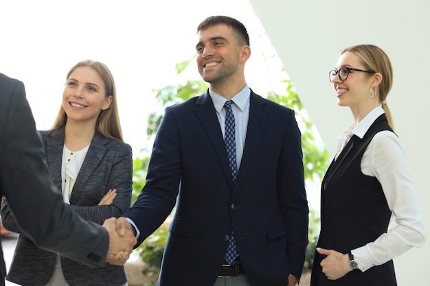 Gente de negocios dándose la mano, terminando una reunión.