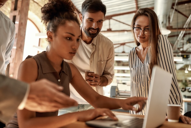 Gente de negocios de día de trabajo ocupado mirando la computadora portátil mientras trabajan juntos en la oficina moderna