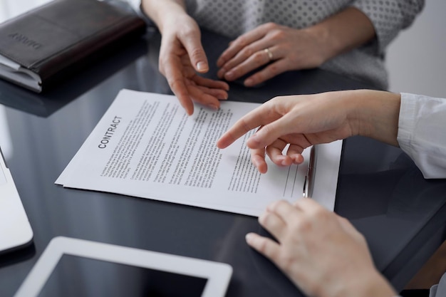 Gente de negocios discutiendo el acuerdo de firma de contrato mientras están sentados en la mesa de cristal en la oficina, primer plano. Socios o abogados trabajando juntos en la reunión. Trabajo en equipo, asociación, concepto de éxito.