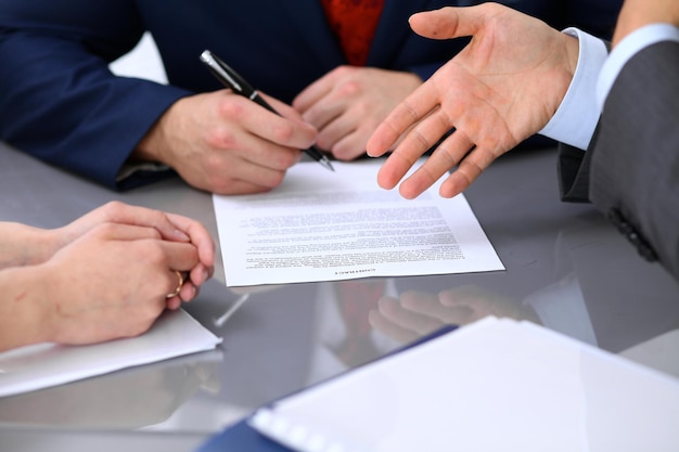 Gente de negocios discutiendo contrato. Cerca de la mano masculina apuntando al papel.