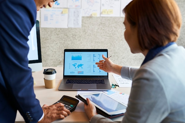 Gente de negocios discutiendo el diagrama en la pantalla del portátil en la reunión y aumentando las ventas y las ganancias de la empresa