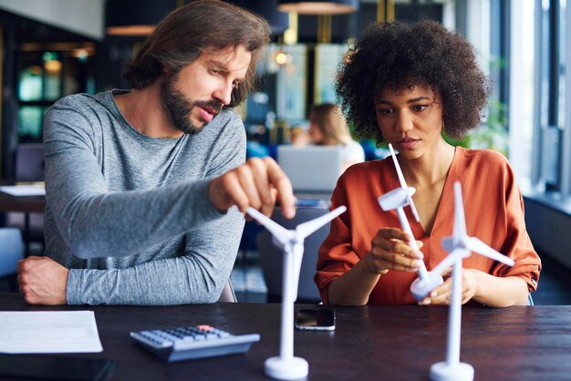 Foto gente de negocios discutiendo sobre modelos de molinos de viento en la mesa en la oficina