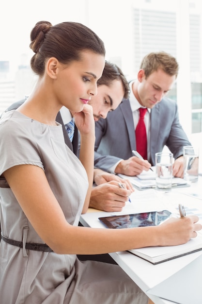 Gente de negocios escribiendo notas en la reunión de la sala de juntas