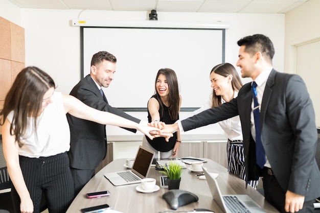 Gente de negocios feliz haciendo un montón de manos para el inicio en la oficina