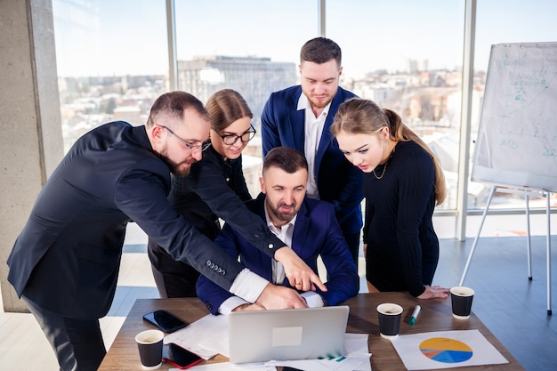 Gente de negocios feliz mirando la presentación de la computadora portátil, éxito en el trabajo, sentado en la oficina moderna. Negociaciones online exitosas. Los empresarios comparten sus conocimientos