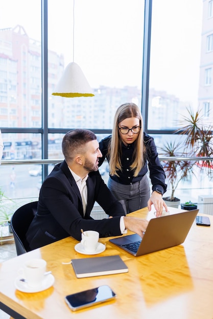 Gente de negocios feliz mirando la presentación de la computadora portátil, éxito en el trabajo, sentado en la oficina moderna. Negociaciones online exitosas. Los empresarios comparten sus conocimientos