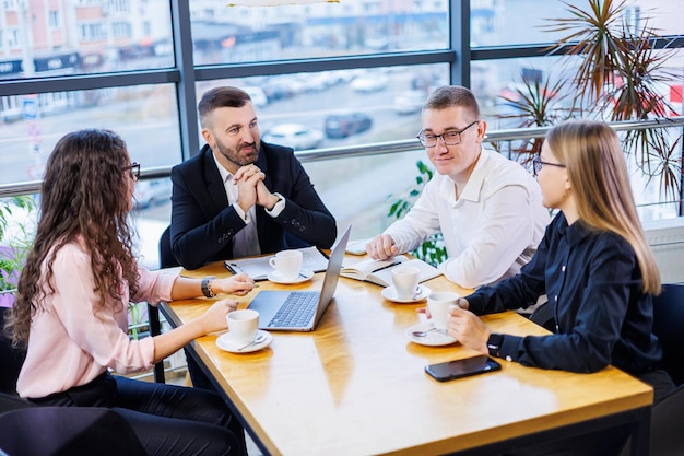 Gente de negocios feliz mirando la presentación de una laptop, éxito en el trabajo, sentada en una oficina moderna. Negociaciones en línea exitosas. Los empresarios comparten sus conocimientos.