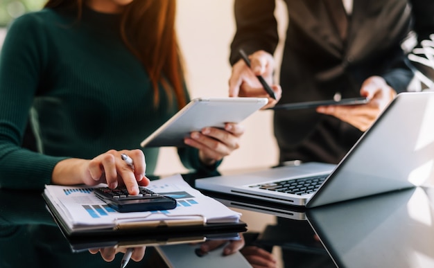 Gente de negocios hablando discutiendo con tablas y gráficos de datos de documentos financieros Reunión de negocios del equipo con teléfono inteligente y computadora portátil y tableta digital