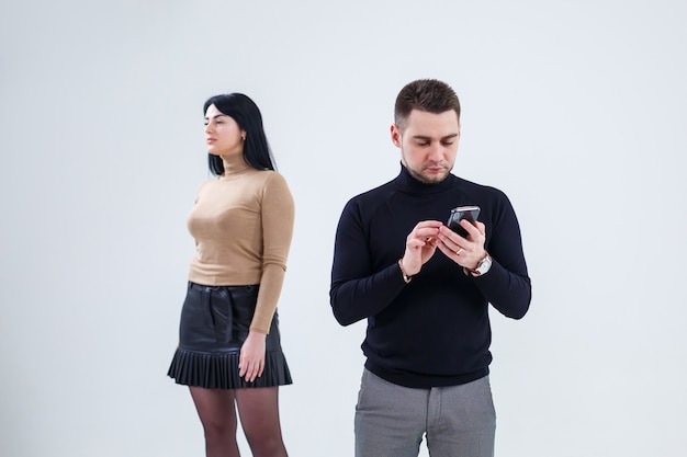 La gente de negocios hombre y mujer miran la pantalla del teléfono. De pie sobre un fondo blanco y hablando de negocios.