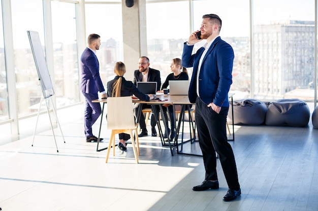 Gente de negocios, hombres de negocios están trabajando juntos en una oficina moderna en un rascacielos de varios pisos. El director está al teléfono. Concepto de trabajo de oficina. Enfoque selectivo