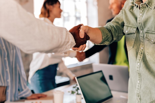 Gente de negocios informal dándose la mano en el trabajo reuniéndose con personas multiétnicas en colaboración