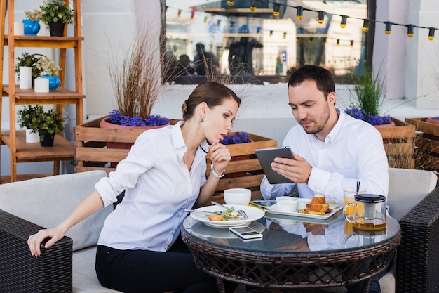 Gente de negocios mirando tableta digital en café durante una reunión