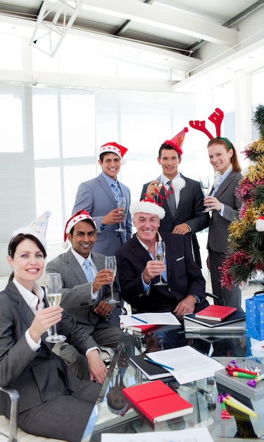 Gente de negocios con la novedad sombrero de navidad brindando en una fiesta