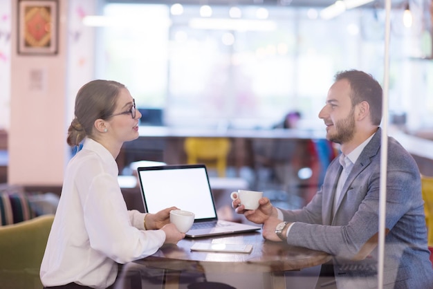 gente de negocios de nueva creación que usa una computadora portátil que se prepara para la próxima reunión mientras toma café y discute ideas en una oficina creativa