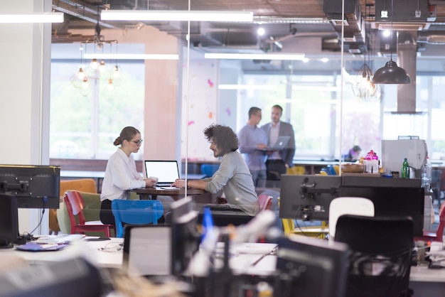 gente de negocios de nueva creación que usa una computadora portátil que se prepara para la próxima reunión mientras toma café y discute ideas en una oficina creativa