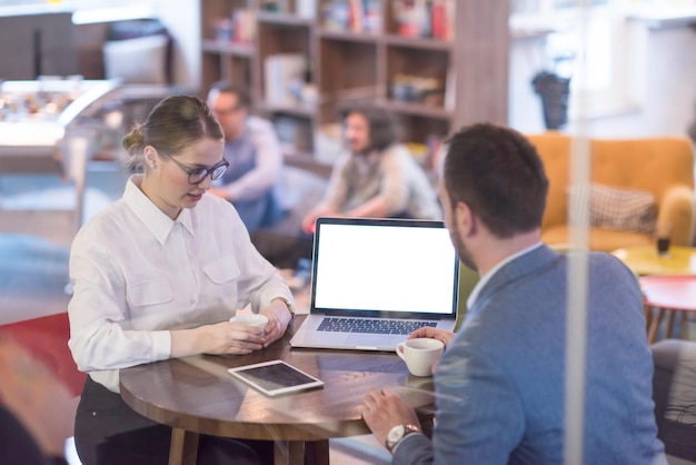 gente de negocios de nueva creación que usa una computadora portátil que se prepara para la próxima reunión mientras toma café y discute ideas en una oficina creativa