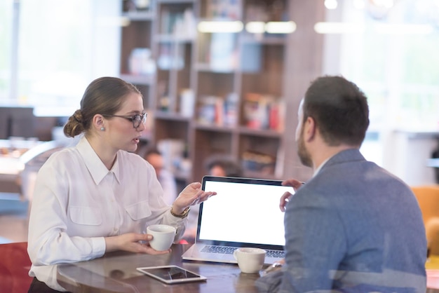 gente de negocios de nueva creación que usa una computadora portátil que se prepara para la próxima reunión mientras toma café y discute ideas en una oficina creativa