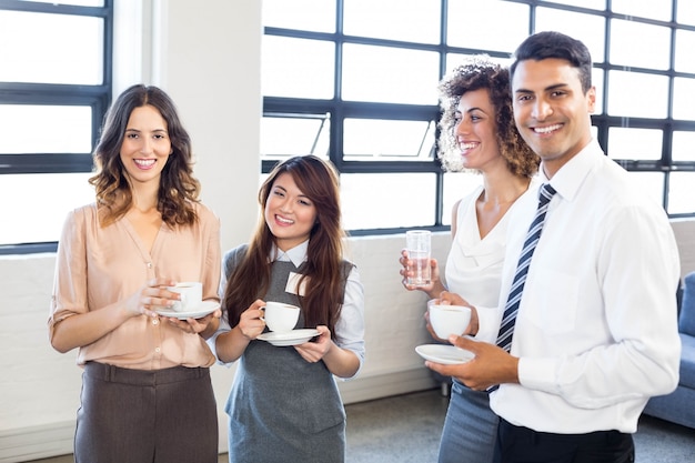 Gente de negocios de pie y juntos y sonriendo en la oficina