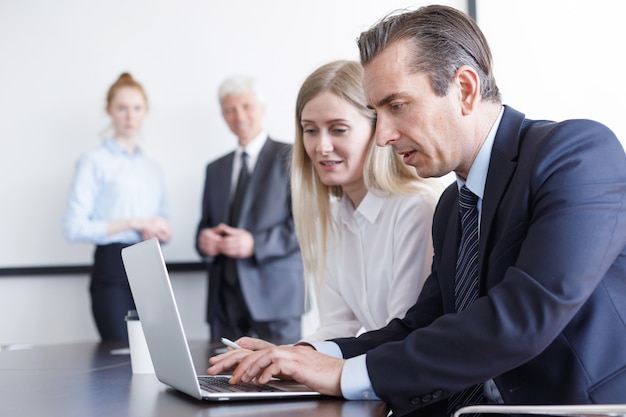 La gente de negocios que trabaja con el portátil juntos en la oficina