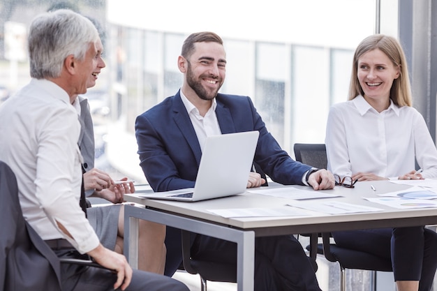 Gente de negocios riendo en el lugar de trabajo sentados en la mesa de conferencias con informes. Concepto de comunicación y reunión de negocios