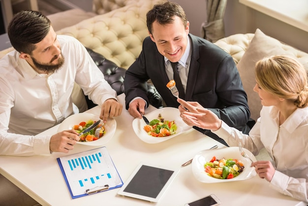 Gente de negocios en ropa formal discutiendo algo durante el almuerzo de negocios