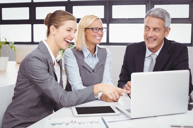 Gente de negocios sonriendo mientras discuten sobre laptop