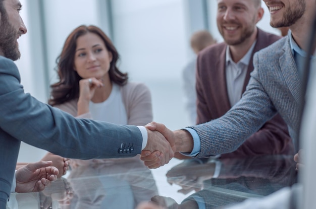 Gente de negocios sonriente dándose la mano en una reunión