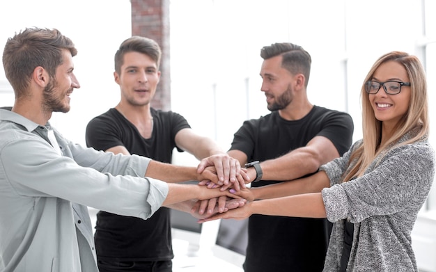 Foto gente de negocios sonriente con la mano apilada durante la reunión en la oficina creativa