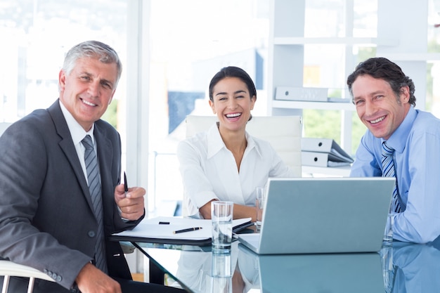 Gente de negocios sonriente que usa la computadora portátil