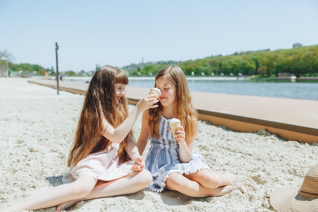 Gente niños amigos y concepto de amistad niñas alegres comiendo helado en la playa